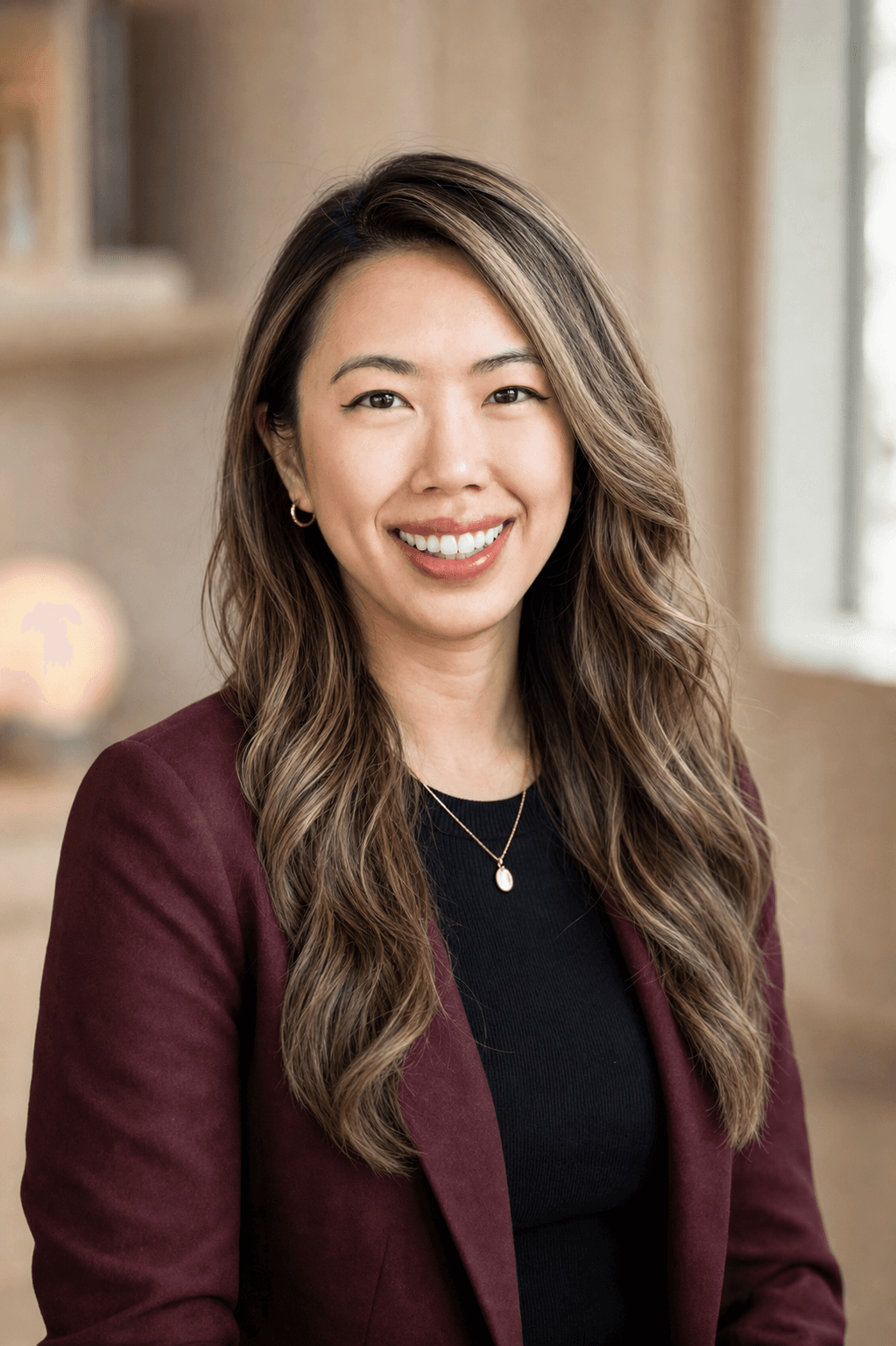 Hillary Lin, MD in an oxblood blazer with long wavy hair