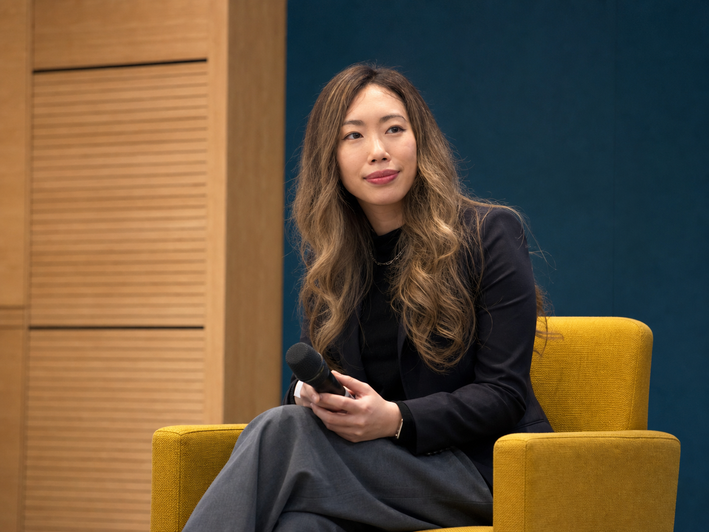 Hillary Lin, MD seated onstage with a handheld microphone